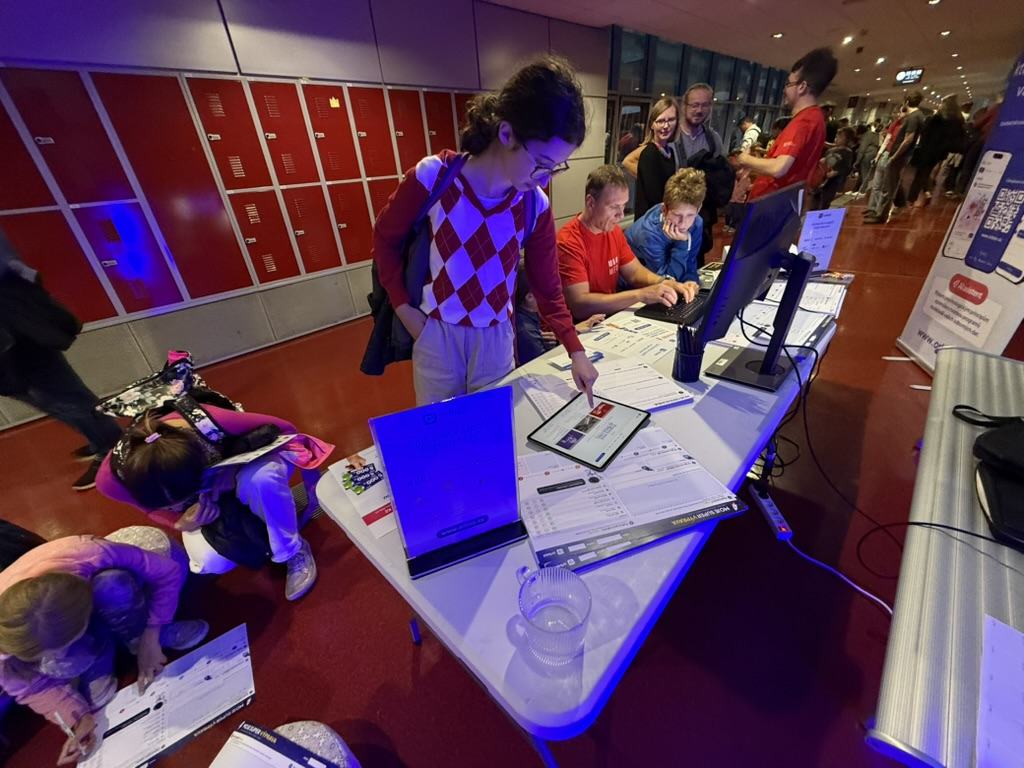 Noc vědy booth on the Brno campus: visitors trying Orbiso on paper and a tablet